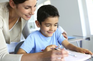 Teacher helping young boy with writing lesson